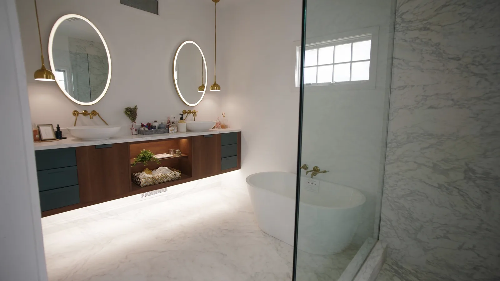 The same bathroom after remodel — floating double vanity, new LVP flooring, recessed lighting, and matte gold fixtures